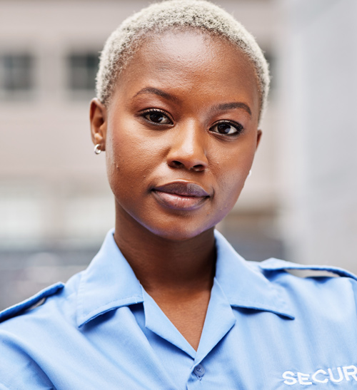 female security professional with short blonde hair wearing a blue uniform standing confidently outdoors