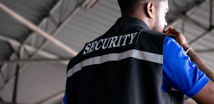 person wearing a security uniform communicating on a radio in a large indoor space